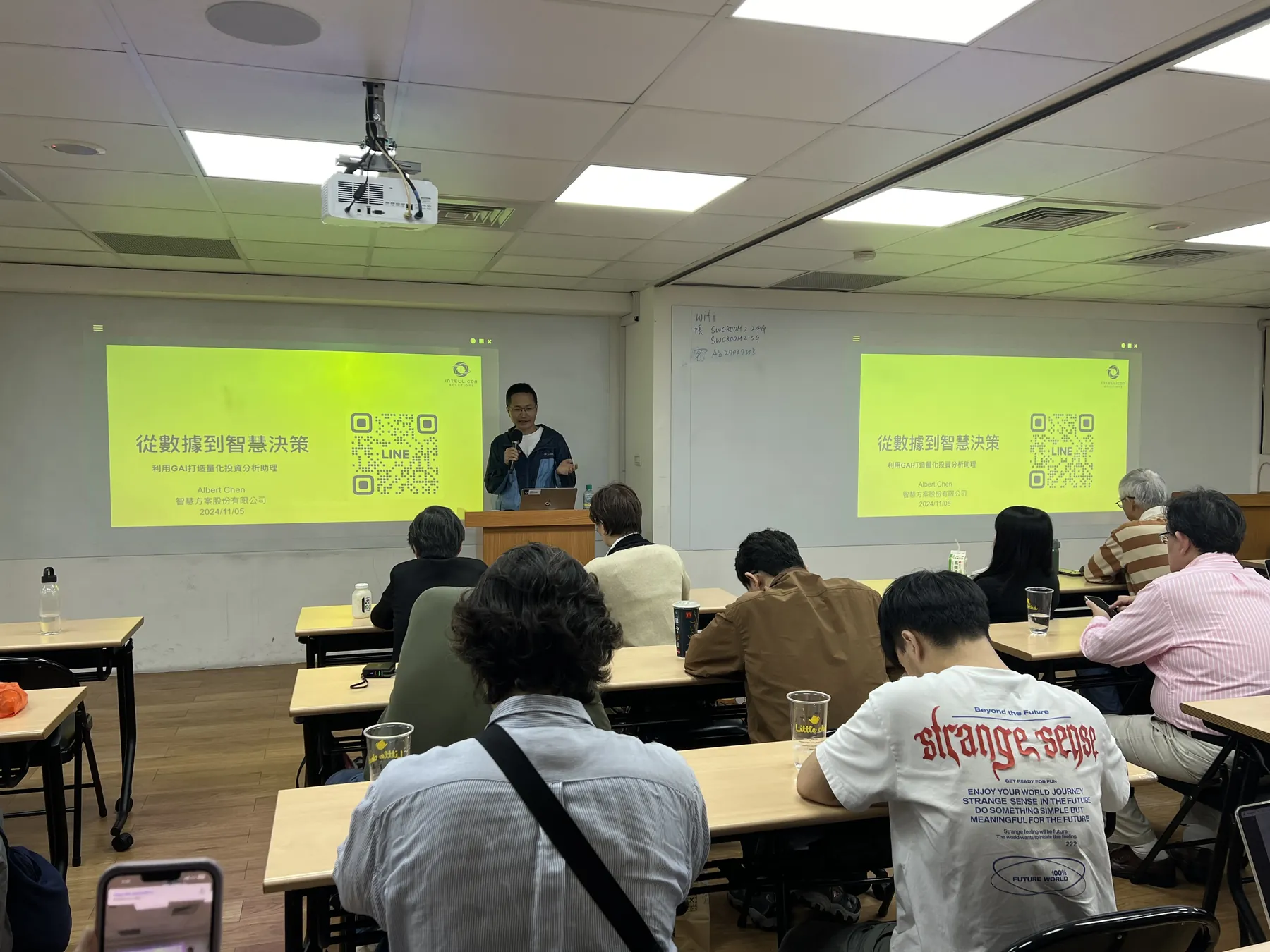 企業の管理職向け講座。二面のスクリーンの前で講師が授業
